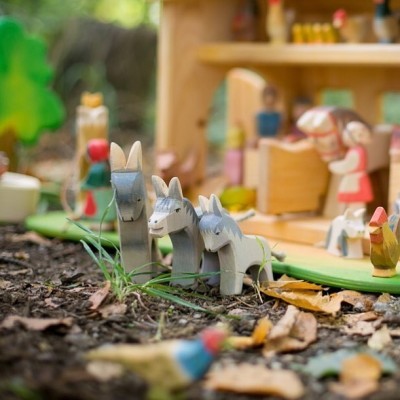 Brinquedos de madeira coloridos de burros e figuras humanas num cenário exterior
