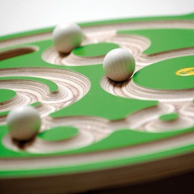Tabuleiro de jogo labirinto em madeira com bolas brancas e áreas verdes.