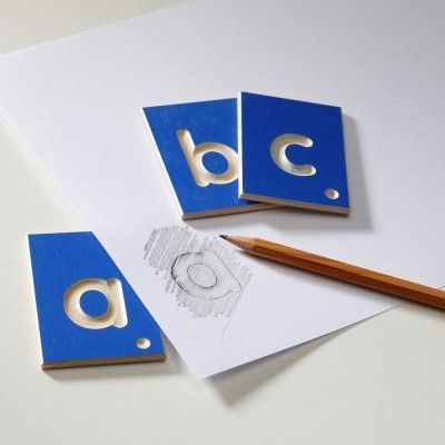 Peças de madeira azuis com letras a, b, c recortadas e lápis sobre papel branco.