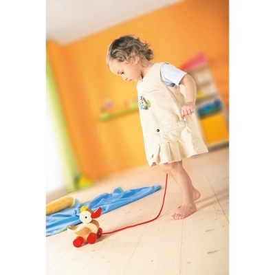 Criança puxando brinquedo de madeira em chão de madeira clara