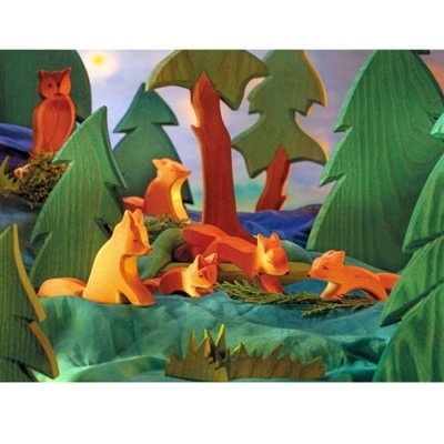 Figuras de madeira pintadas de raposas e árvores em cenário de floresta