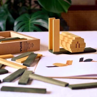 Peças de madeira Kapla de cores natural e verde com caixa e manual sobre mesa branca