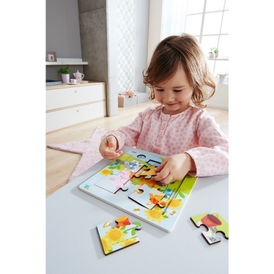 Menina a montar puzzle de madeira colorido numa mesa branca