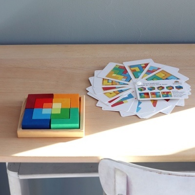 Puzzle de madeira colorido com peças e cartas sobre mesa clara