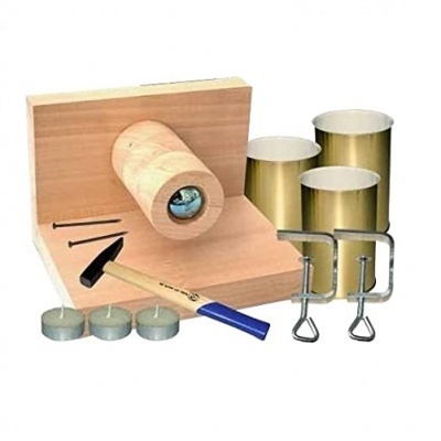Conjunto de ferramentas e acessórios para fabricação de velas com suporte em madeira, martelo e recipientes metálicos dourados.