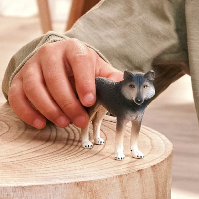 Figura de lobo cinza, branco e preto segurada por uma mão de criança