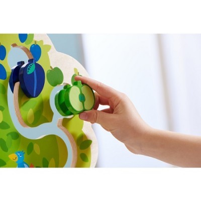 Peças de madeira em forma de frutas verdes e azuis num painel colorido de madeira em formato de árvore