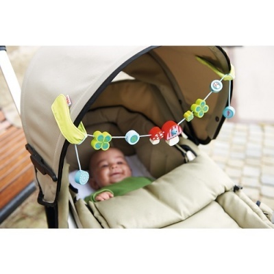 Carrinho de bebé bege com brinquedo pendente colorido e bebé sorridente