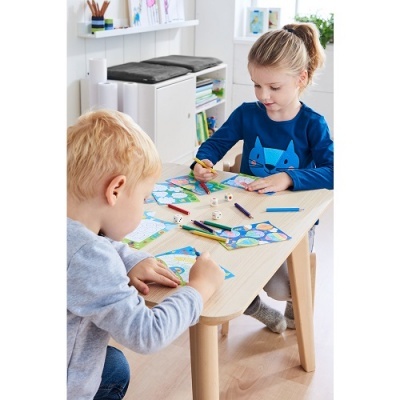 Duas crianças pintando em mesa de madeira clara com lápis de cor e dados de madeira