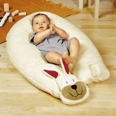 Bebé deitado em almofada felpuda branca em forma de coelho com rosto sorridente