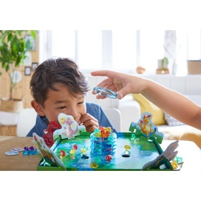 crianças a jogar jogo de tabuleiro com dinossauros e peças coloridas em mesa interior