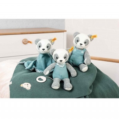 Três peluches panda em tecido cinza e branco com roupas azuis sobre cobertor verde-escuro