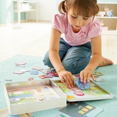 Menina a montar puzzle colorido num tapete azul