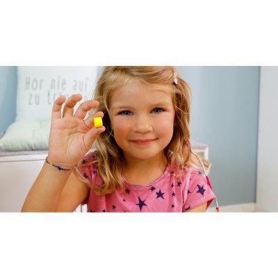 Criança segurando bloco amarelo quadrado com parede azul claro ao fundo