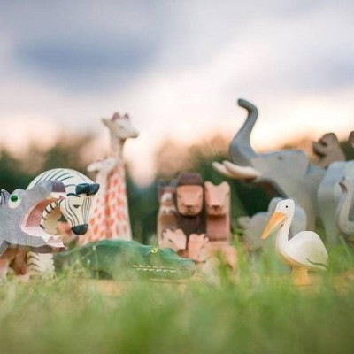 Figuras de animais de madeira coloridas ao ar livre numa composição de safari.