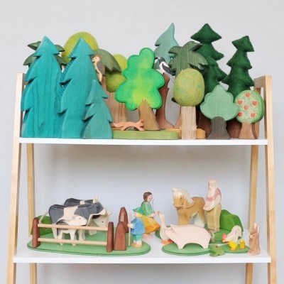 Brinquedos de madeira representando árvores e animais de fazenda, organizados em estante branca com estrutura de madeira