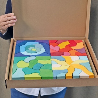 Conjunto de mosaicos coloridos em madeira encaixáveis numa caixa de cartão.