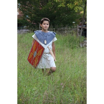 Criança vestida como romano com escudo vermelho e espada branca em relva alta