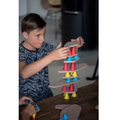 Menino a empilhar cones coloridos de madeira numa tabela de pranchas