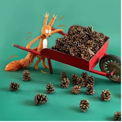 Carrinho de mão vermelho cheio de pinhas e um esquilo de pelúcia laranja empurrando