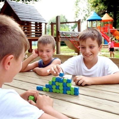 Três meninos a jogar com blocos de construção coloridos num parque infantil