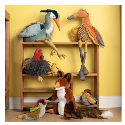 Peluches de animais variados numa estante de madeira, com fundo amarelo.