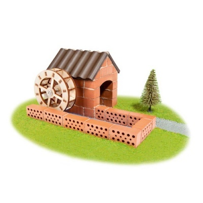 Mini moinho de água em tijolos com roda de madeira e telhado castanho, em base verde com árvore e caminho