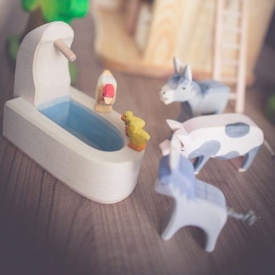 Brinquedos de madeira com animais e bebedouro branco com azul