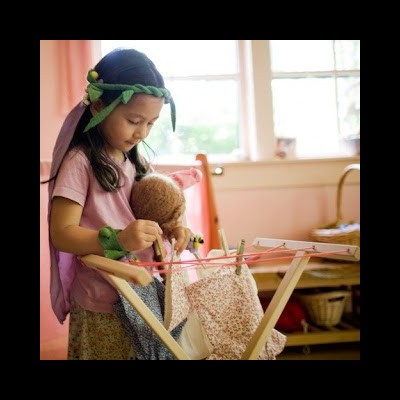 Criança a brincar com marioneta num quarto cor de rosa, usando tiara e pulseira verdes