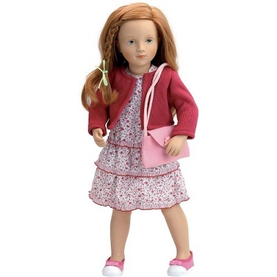 Boneca com vestido floral, casaco vermelho e mala rosa, fundo branco