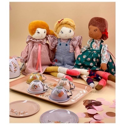 Três bonecas de pano com roupas coloridas e conjunto de chá de brinquedo sobre mesa