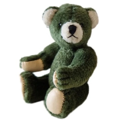 Ursinho de pelúcia verde com detalhes creme sentado