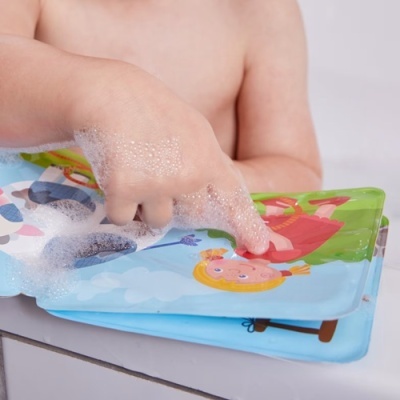 Mão de criança a tocar livro de banho com ilustrações coloridas e espuma