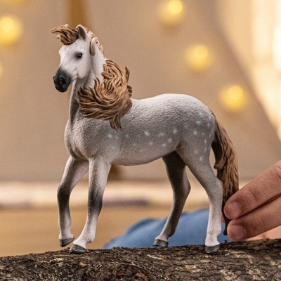 Figura miniatura de cavalo cinzento com crina castanha sobre madeira
