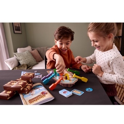 Crianças a jogar um jogo de tabuleiro com peças coloridas de plástico e cartas