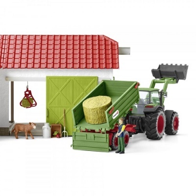 Miniatura de trator verde com reboque e cenário agrícola com celeiro, bala de feno, vaca e figura humana