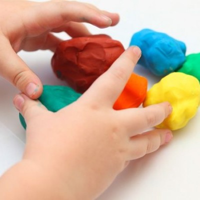 Mãos de criança a manusear massa de modelar colorida