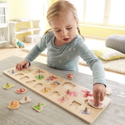 Menina a brincar com um puzzle de letras de madeira coloridas numa mesa num quarto iluminado