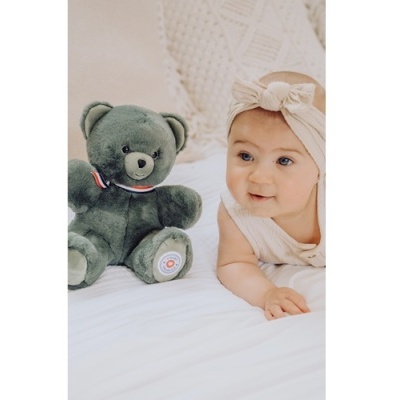 Urso de peluche cinzento e bebé com faixa beige na cama branca