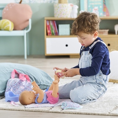 Criança a brincar com boneca e mochila florida no chão de casa