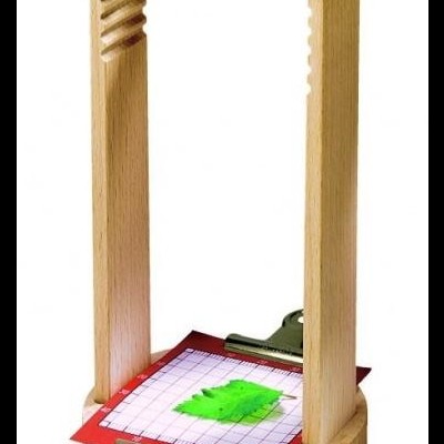 Aparelho em madeira com lente de vidro verde e cartão quadrículado com folha