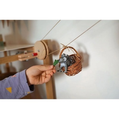 Figuras decorativas de um rato num cesto suspenso por fios com uma mão a oferecer folha verde