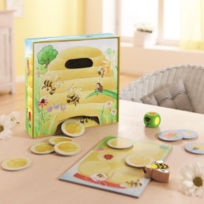 Jogo de tabuleiro infantil com tema abelhas e mel sobre mesa clara com flores brancas