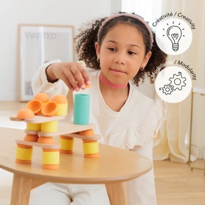 Menina a brincar com blocos de construção macios coloridos sobre mesa de madeira