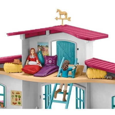 Casa de brinquedo com telhado vermelho, bonecas e cata-vento dourado em forma de cavalo