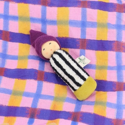 Boneco tecido com chapéu roxo sobre tecido quadriculado colorido