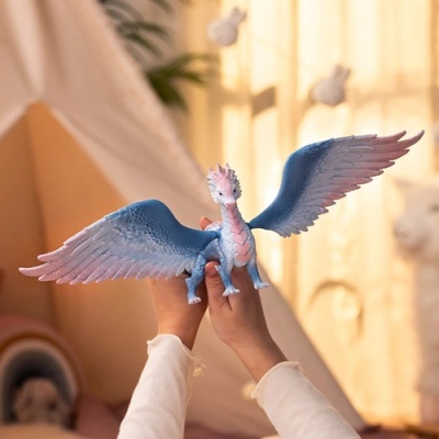 Figura de dragão azul com asas abertas segurada por duas mãos