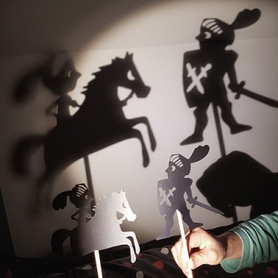 Sombras chinesas de cavalo e cavaleiro em papel preto em frente a parede branca