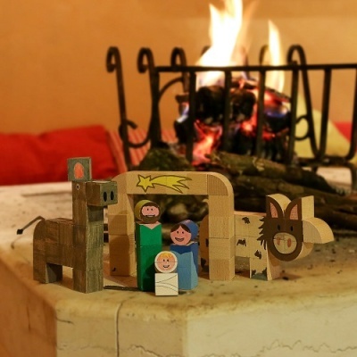 Presépio em madeira com figuras pintadas à mão junto a lareira com fogo