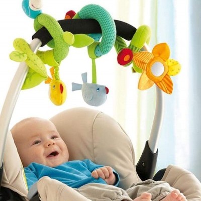 Brinquedo colorido macio pendurado num carrinho com bebé sentado